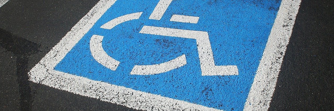 markierter Parkplatz mit einem blau/weißen Rollstuhl-Piktogramm