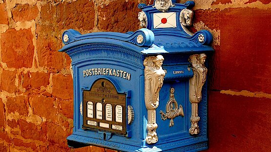 blauer Briefkasten auf einer roten Backsteinwand